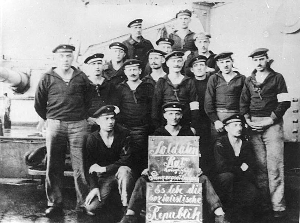 Matrosen an Deck des Linienschiffs Prinzregent Luitpold mit einer Tafel: „Soldatenrat Kriegsschiff Prinzregent Luitpold. Es lebe die sozialistische Republik.“