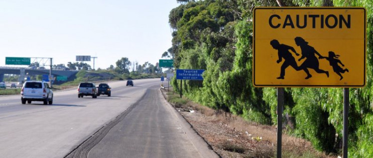 Kurz hinter der Grenze bei Tijuana warnt ein Schild Autofahrer vor Flüchtlingsfamilien, die die Fahrbahn überqueren könnten – sie sollen nun vom Militär aufgehalten werden. (Foto: Jonathan McIntosh)