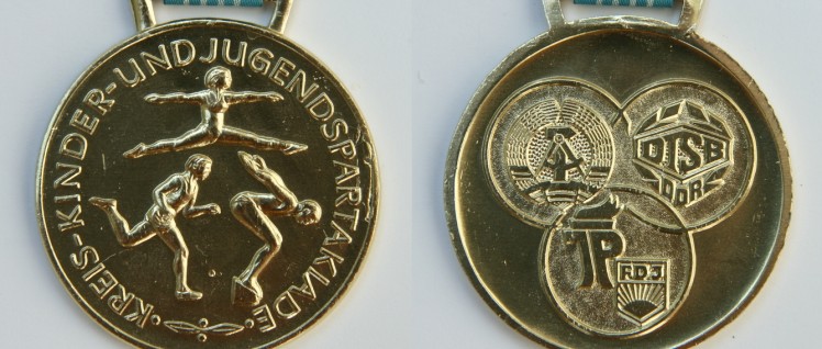 Medaillenregen für den Breitensport: Gold bei der Kreisspartakiade in der DDR (Foto: https://commons.wikimedia.org/wiki/File:Kreisspartakiade_DDR_Goldmedaille_1988.jpg)