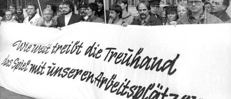 Stahlarbeiter der Maxhütte Unterwellenborn protestieren 1990 gegen die Treuhandanstalt. (Foto: [url=https://de.wikipedia.org/wiki/Treuhandanstalt#/media/Datei:Bundesarchiv_Bild_183-1990-1219-006,_Berlin,_Stahlwerker_protestieren_vor_Treuhandanstalt.jpg]Bundesarchiv, Bild 183-1990-1219-006 / Franke, Klaus[/url])