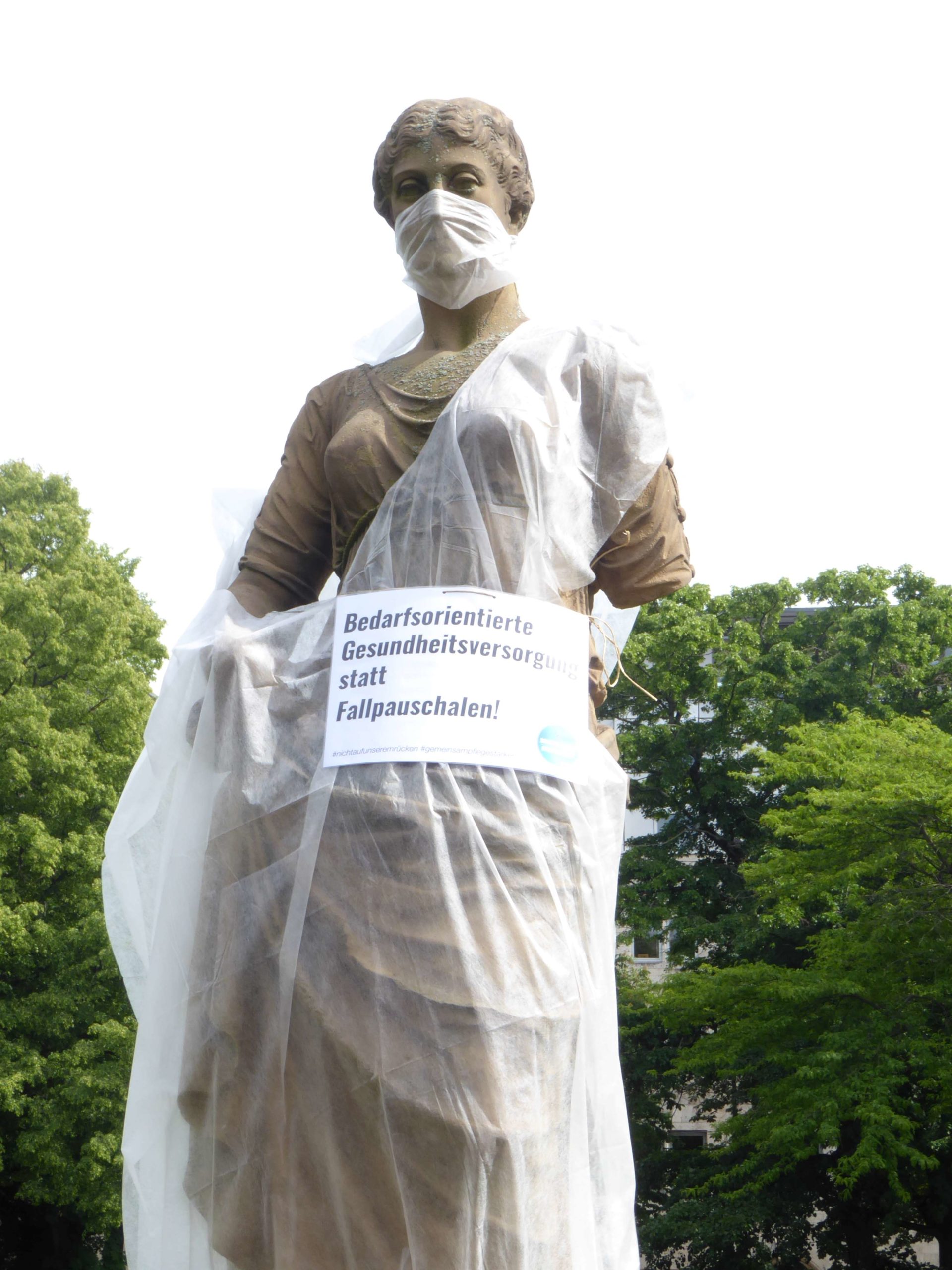 Statue mit Schild scaled - Tag der Pflege in Stuttgart - DKP, Gesundheitssystem, Pflege, Stuttgart - Blog