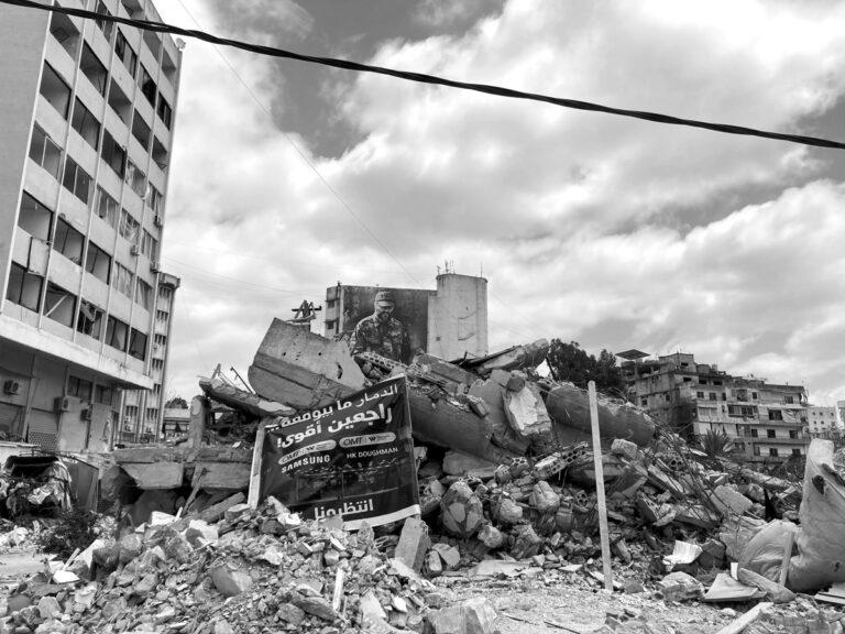 2413 Foto K. Leukefeld. Nabatieh. Auf dem Plakat in den Truemmern steht Wir kommen wieder und zwar staerker - Wer schützt die Libanesen? - Flüchtlinge, Hisbollah, Israelische Kriegsführung, Krieg gegen Libanon, Vertreibung - Internationales